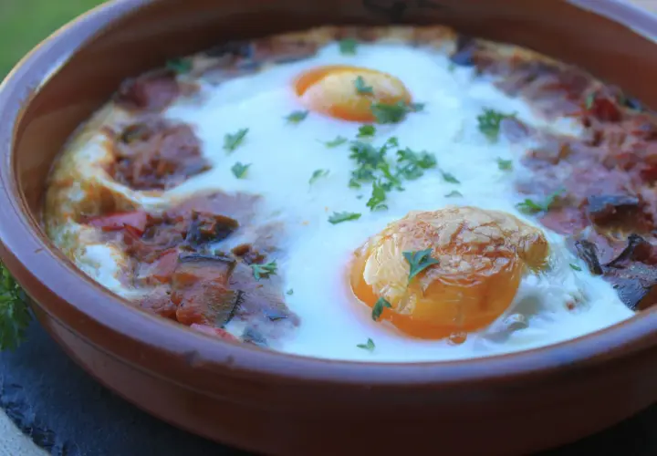 Un plato de samfaina con huevos escalfados, decorado con perejil fresco. ¡Una delicia para probar esta samfaina recepta!