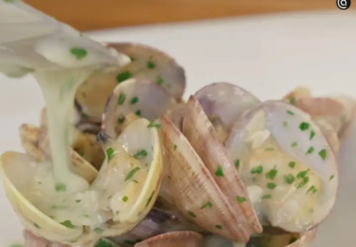 Almejas en salsa verde, con una cremosa salsa blanca y perejil picado, listas para ser servidas.