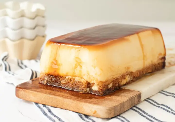 Tarta de cuajada rectangular con caramelo líquido, servida sobre tabla de madera.