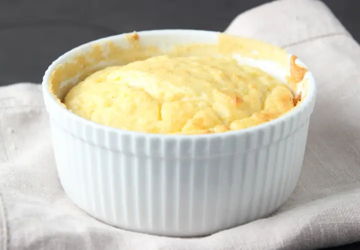 Un esponjoso soufflé de patatas recién horneado en un ramekin blanco, listo para ser disfrutado.