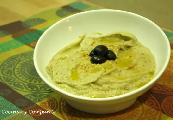 Un cremoso puré de berenjena con aceite de oliva y aceitunas negras, listo para disfrutar.