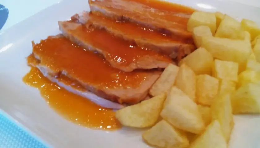 Jamon asado al horno, jugoso y tierno, bañado en salsa y acompañado de patatas fritas crujientes. ¡Un plato delicioso!