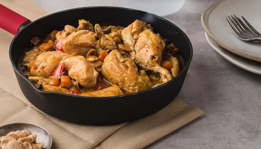 Sabroso pollo con almendras y verduras en una sartén, listo para servir.
