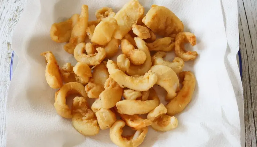 Un plato lleno de chocos fritos, crujientes y dorados, reposando sobre papel absorbente. ¡Un aperitivo delicioso!