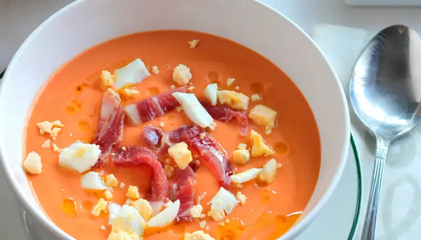 Salmorejo cremoso con jamón serrano y huevo duro picado, ingredientes clave de esta delicia.