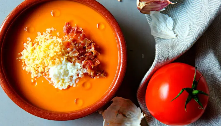 Salmorejo cremoso hecho en Thermomix, servido en cuenco de barro con huevo duro picado y taquitos de jamón.