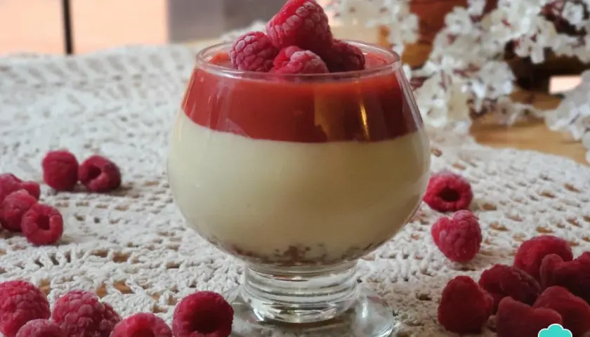 Deliciosa tarta de queso sin horno en copa, coronada con frambuesas frescas y coulis de frutos rojos.