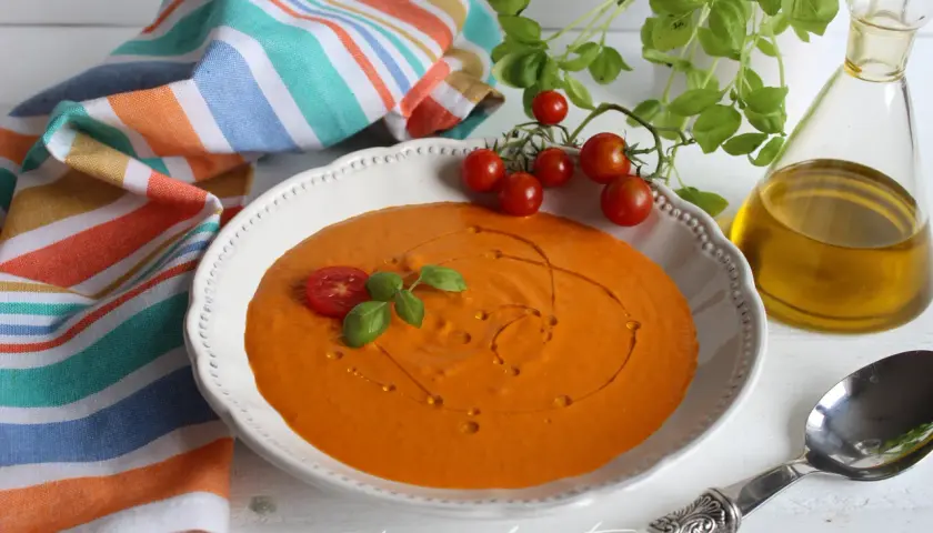 Crema de queso de tomate, decorada con tomates cherry y albahaca, lista para disfrutar.