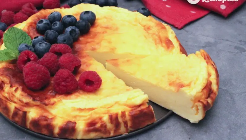 Tarta de yogur griego dorada, decorada con frambuesas y arándanos frescos. ¡Una delicia!