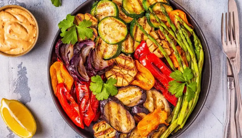Plato de verduras a la brasa: calabacín, berenjena, pimientos, cebolla, espárragos y ajo, con un toque de limón y salsa.