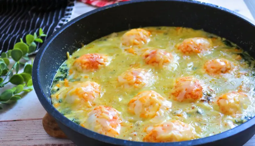 Deliciosos espinacas a la crema gratinadas con queso en una sartén.