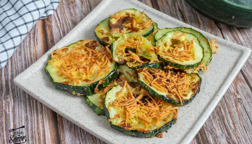 Rodajas de calabacín airfryer crujientes y doradas, espolvoreadas con queso rallado. ¡Un aperitivo saludable y delicioso!