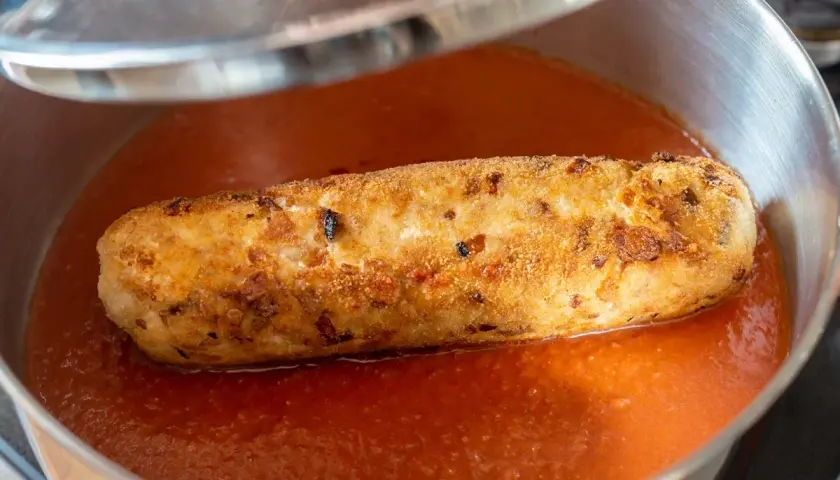 Rollo de bonito casa consuelo, dorado y crujiente, nadando en una salsa de tomate casera en una sartén.