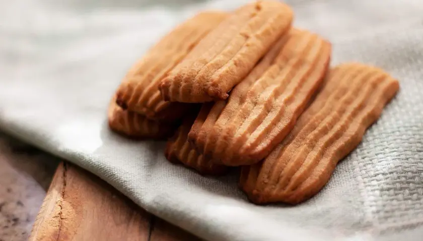 Galletas de mantequilla receta: deliciosas galletas doradas con surcos, apiladas sobre una tela clara.