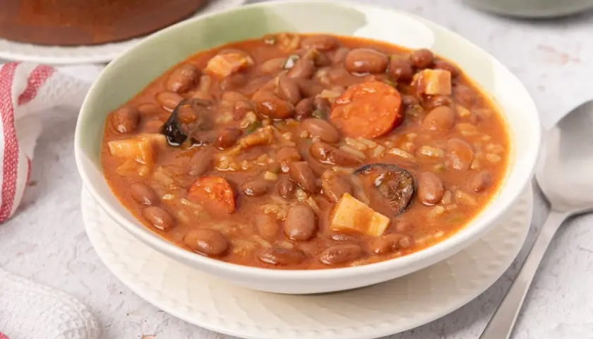 Un tazón humeante de alubias pintas con chorizo, patatas y arroz. Un plato reconfortante y sabroso.