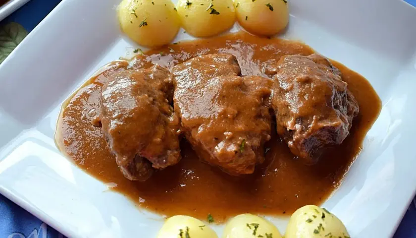 Carrilleras de ternera estofadas en salsa, acompañadas de patatas cocidas y espolvoreadas con perejil. Un plato casero que invita a disfrutar.