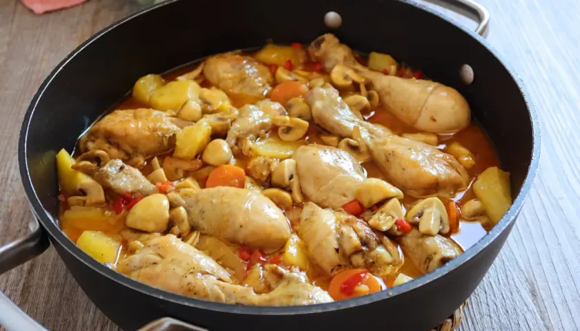 Estofado de pollo casero con patatas, champiñones y zanahorias en una sartén. Un plato reconfortante y delicioso.