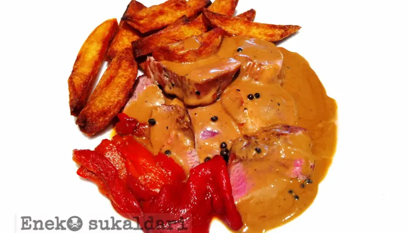Delicioso solomillo a la pimienta bañado en salsa cremosa, acompañado de patatas rústicas y pimientos rojos asados.