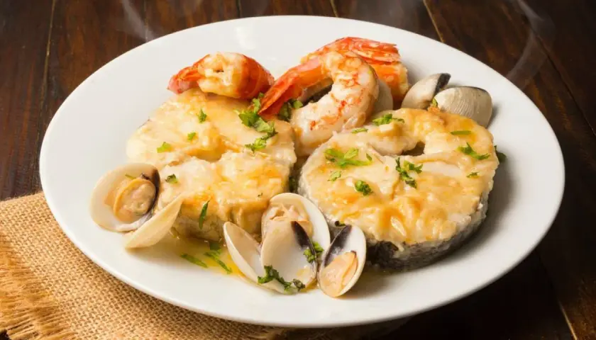 Merluza a la marinera con almejas y gambas, un plato delicioso y aromático, listo para disfrutar.