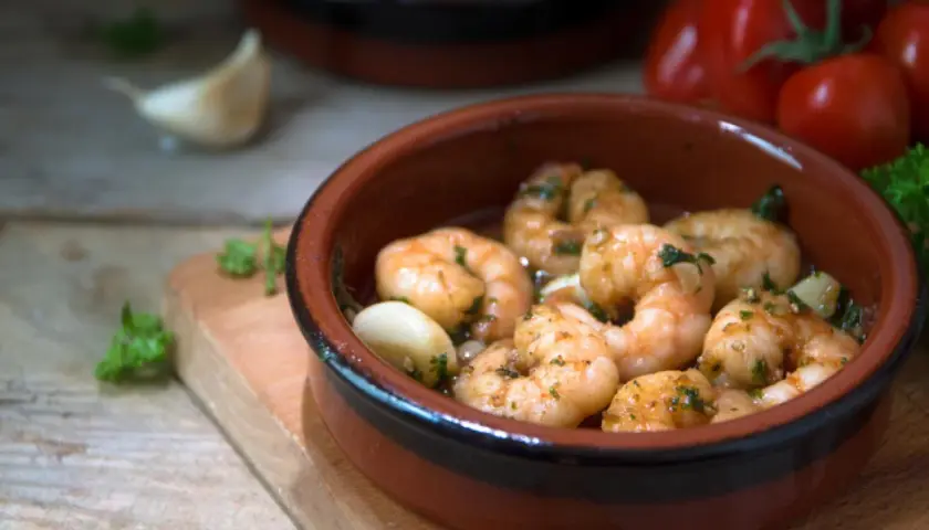 Deliciosos langostinos al ajillo, servidos en cazuela de barro con ajo y perejil.