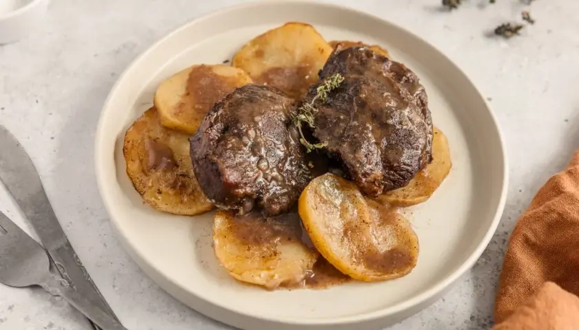Deliciosas galtas al horno, tiernas y jugosas, servidas sobre rodajas de patata doradas y bañadas en su propia salsa.