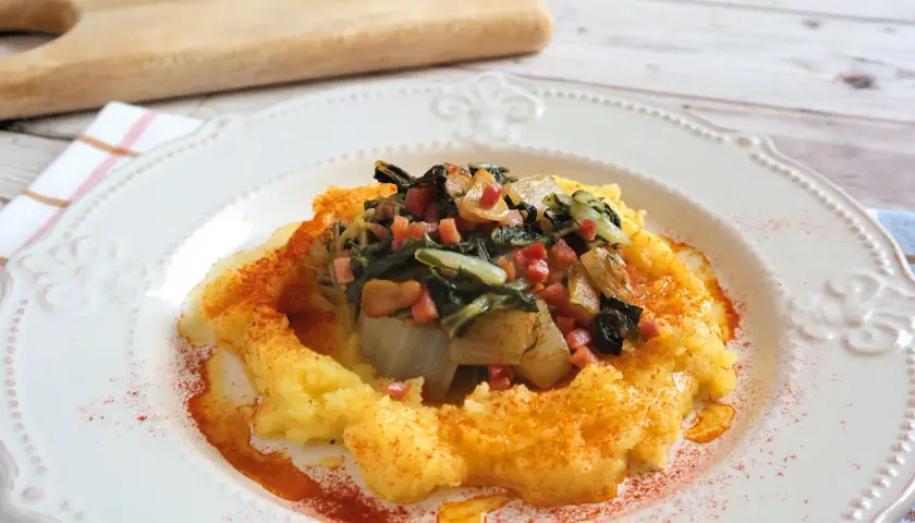 Puré de patatas cremoso con un sofrito de acelgas y trocitos de jamón, espolvoreado con pimentón. Un plato reconfortante de acelgas con patatas.