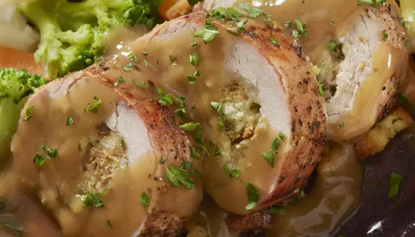 Jugoso solomillo de pollo relleno, bañado en salsa y acompañado de brócoli y zanahoria.