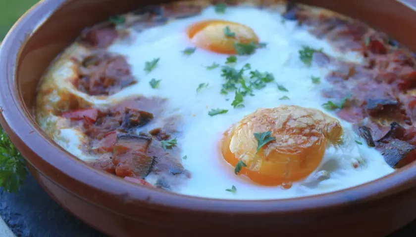 Un plato de samfaina con huevos escalfados, decorado con perejil fresco. ¡Una delicia para probar esta samfaina recepta!