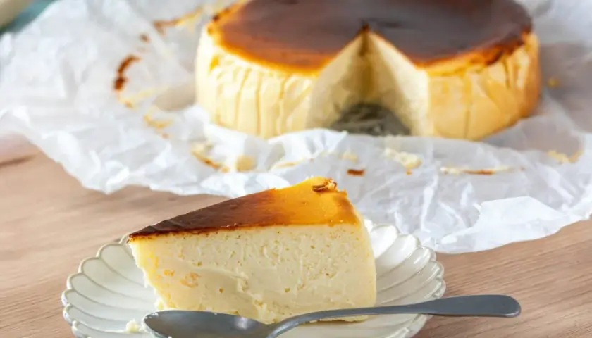 Deliciosa tarta de queso en freidora de aire, con una porción servida en plato y cuchara.