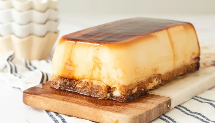 Tarta de cuajada rectangular con caramelo líquido, servida sobre tabla de madera.