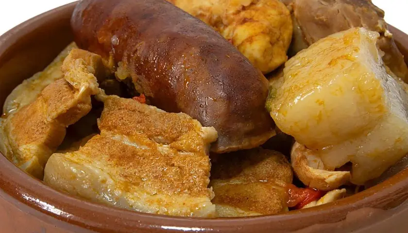 Un reconfortante puchero andaluz en cazuela de barro, con chorizo, tocino y trozos de carne.