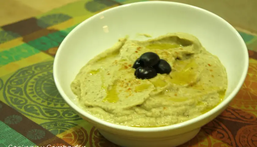 Un cremoso puré de berenjena con aceite de oliva y aceitunas negras, listo para disfrutar.