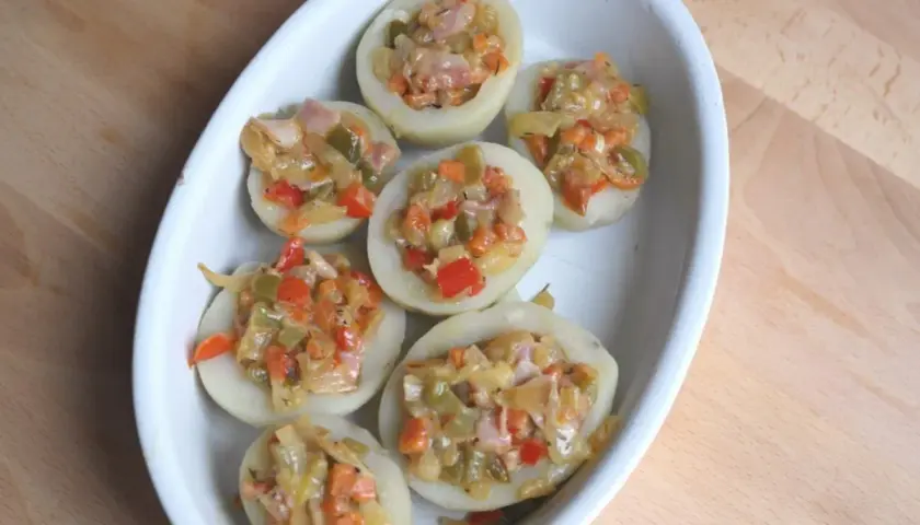 Patatas rellenas con verduras y jamón, listas para hornear. Un plato casero y delicioso.