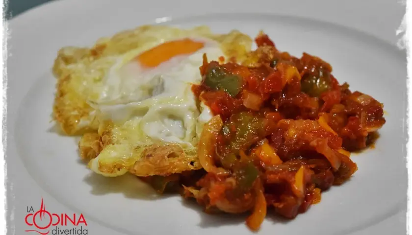 Huevo frito con un sofrito de pimientos y tomate. Un plato sencillo y delicioso, perfecto para cualquier momento del día.
