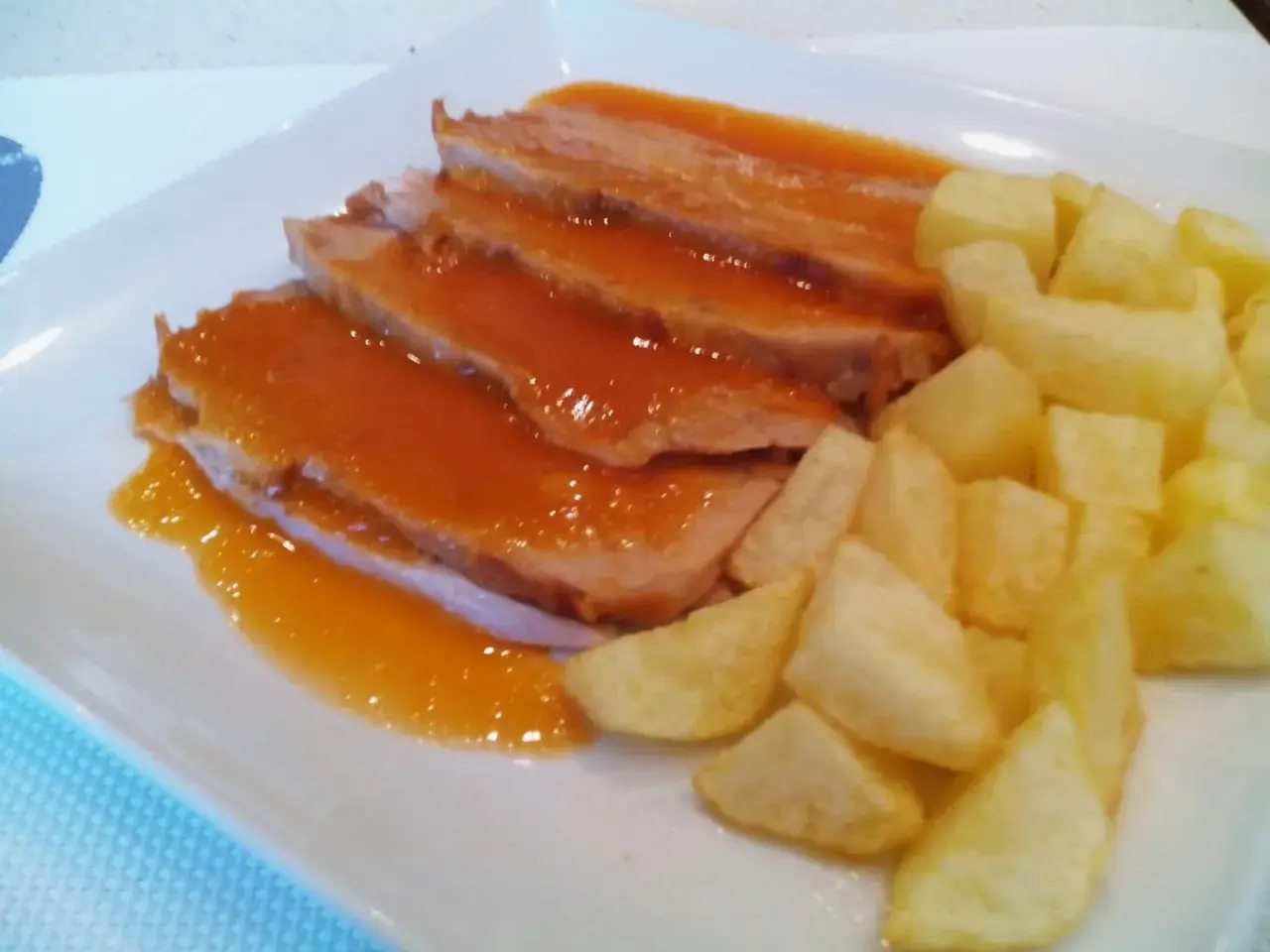 Jamon asado al horno, jugoso y tierno, bañado en salsa y acompañado de patatas fritas crujientes. ¡Un plato delicioso!
