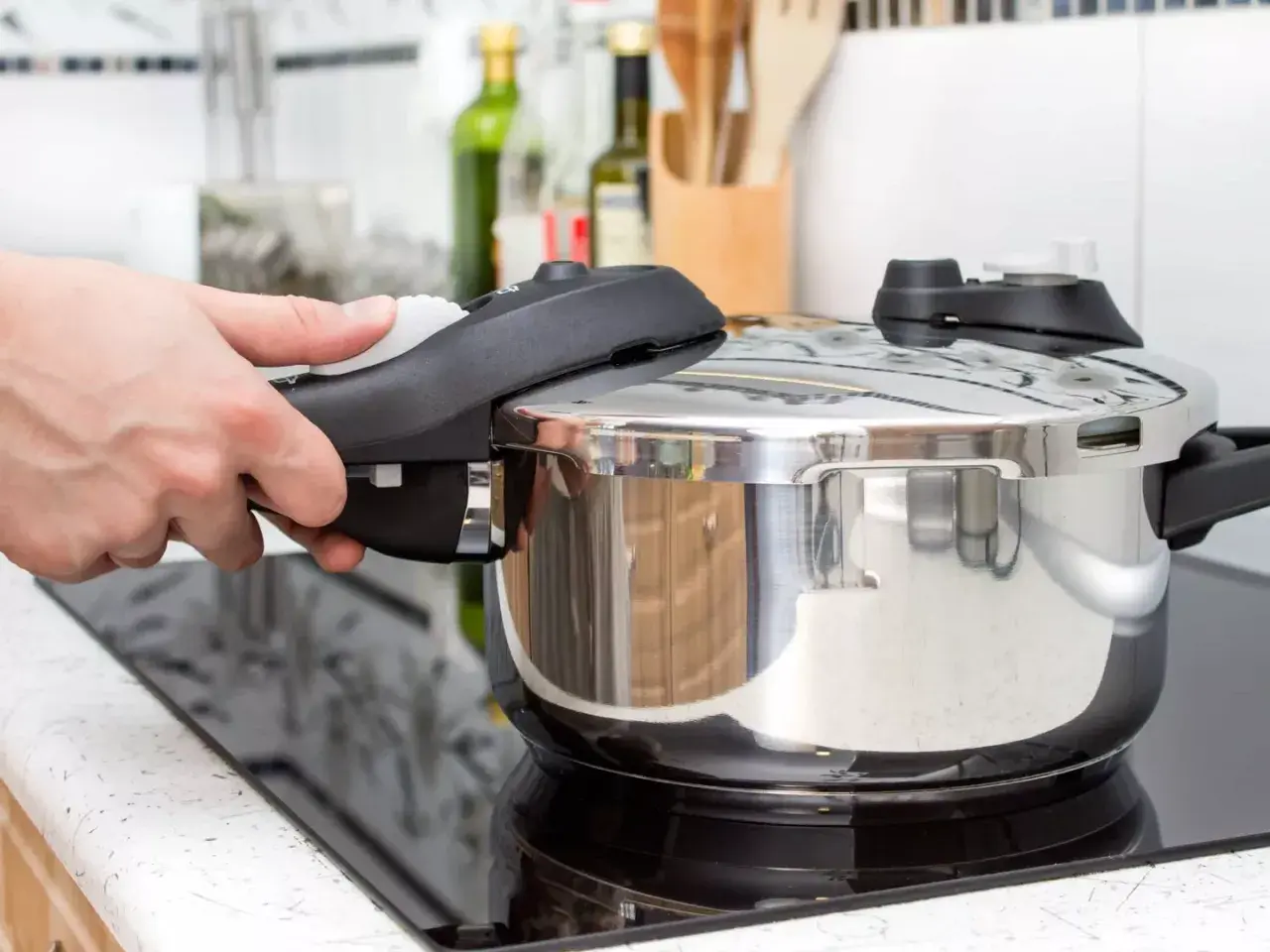 Mano cerrando la tapa de una olla express para cocinar lentejas. Cocina rápida y sabrosa.