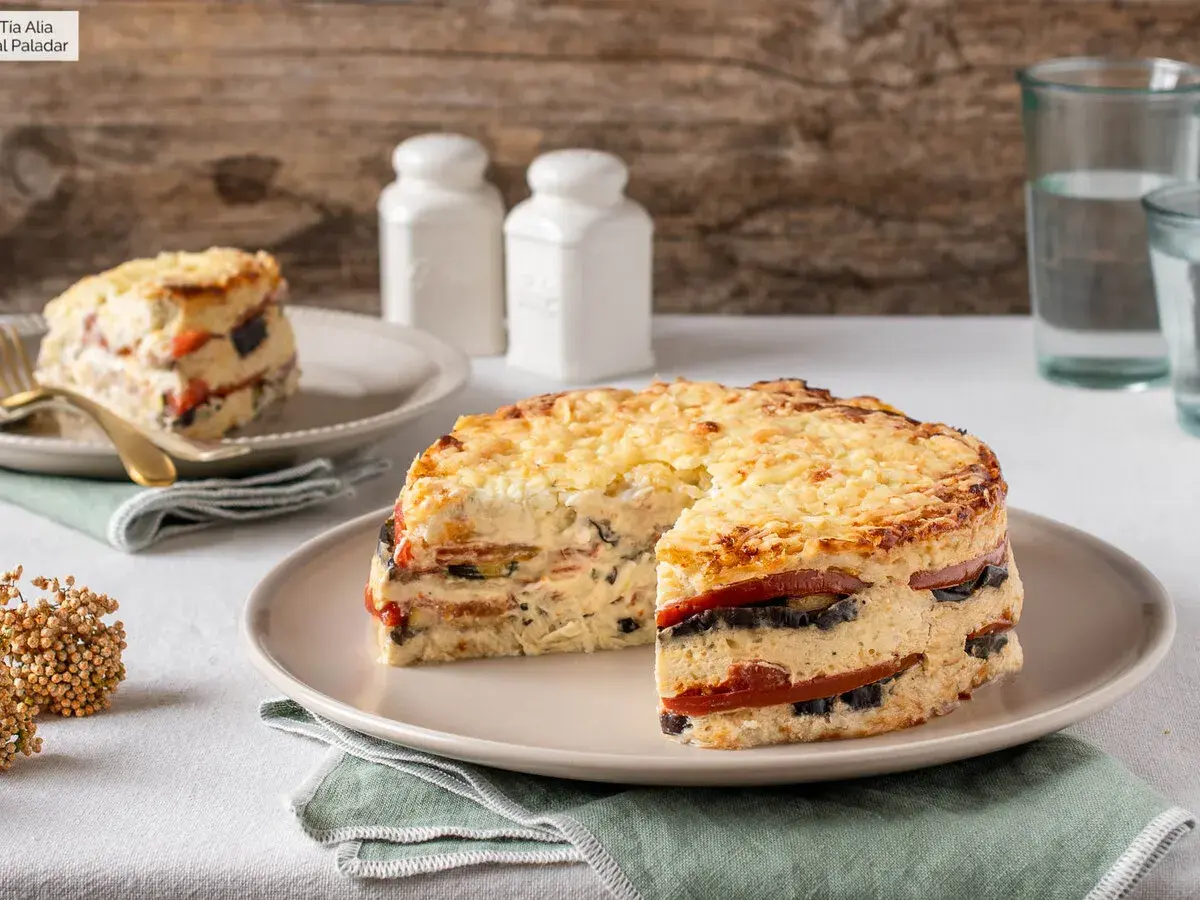 Pastel de verduras en capas, gratinado con queso, servido en un plato.
