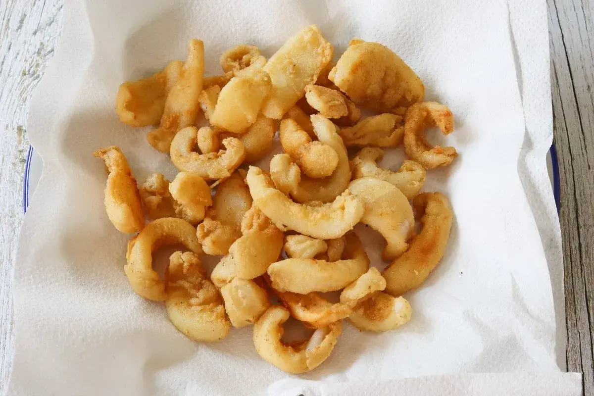 Un plato lleno de chocos fritos, crujientes y dorados, reposando sobre papel absorbente. ¡Un aperitivo delicioso!