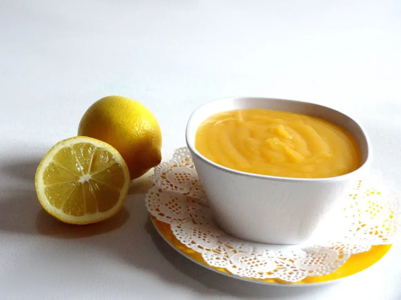Un tazón de crema de limón, con limones frescos al lado.