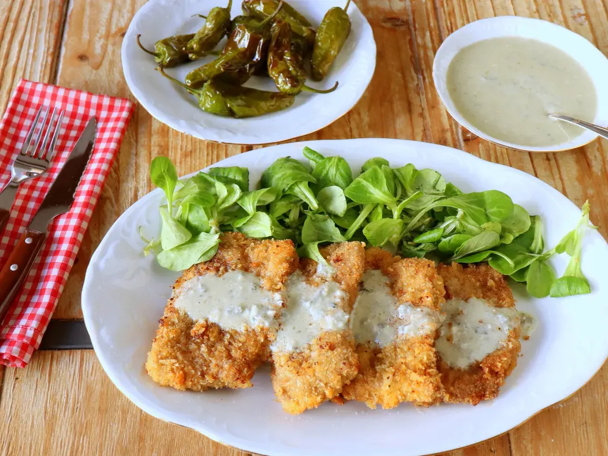 Escalopines al cabrales crujientes, servidos con ensalada verde y pimientos asados. ¡Un plato delicioso!