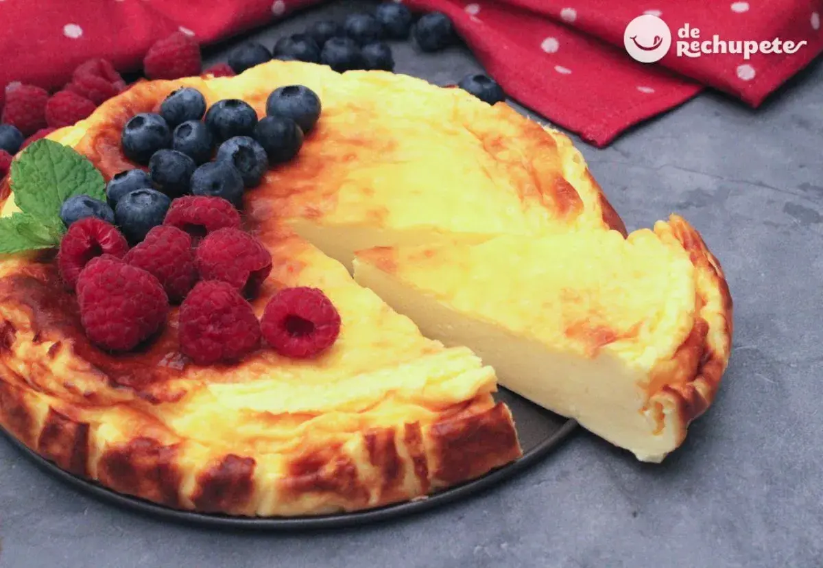 Tarta de yogur griego dorada, decorada con frambuesas y arándanos frescos. ¡Una delicia!