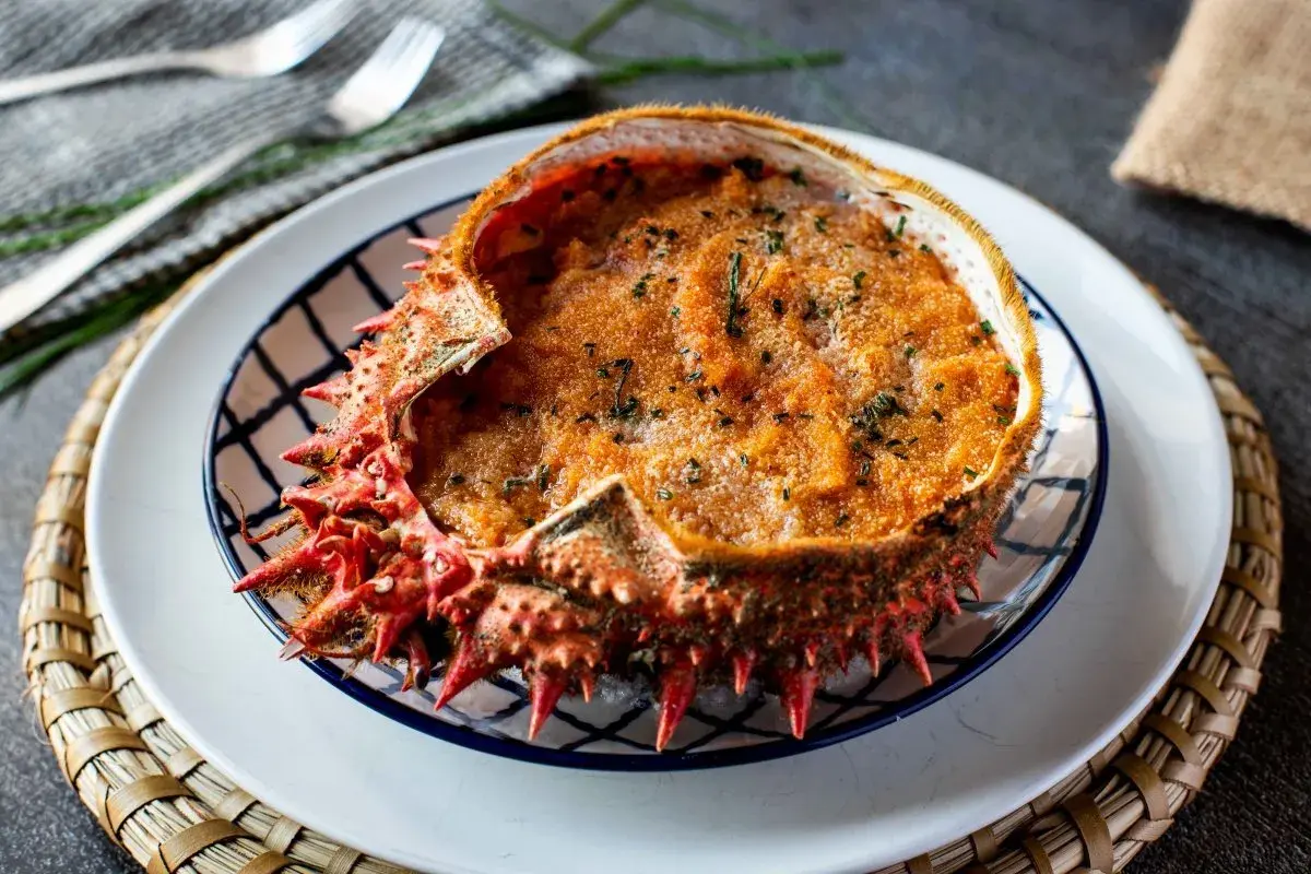 Txangurro a la donostiarra, un delicioso relleno de marisco gratinado en su propio caparazón, adornado con perejil picado.