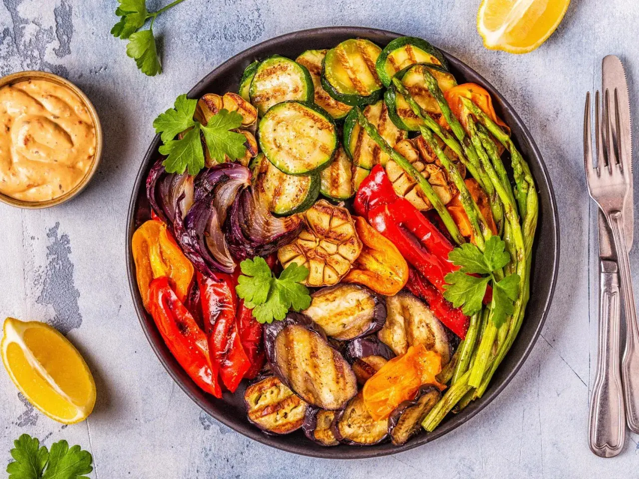 Plato de verduras a la brasa: calabacín, berenjena, pimientos, cebolla, espárragos y ajo, con un toque de limón y salsa.