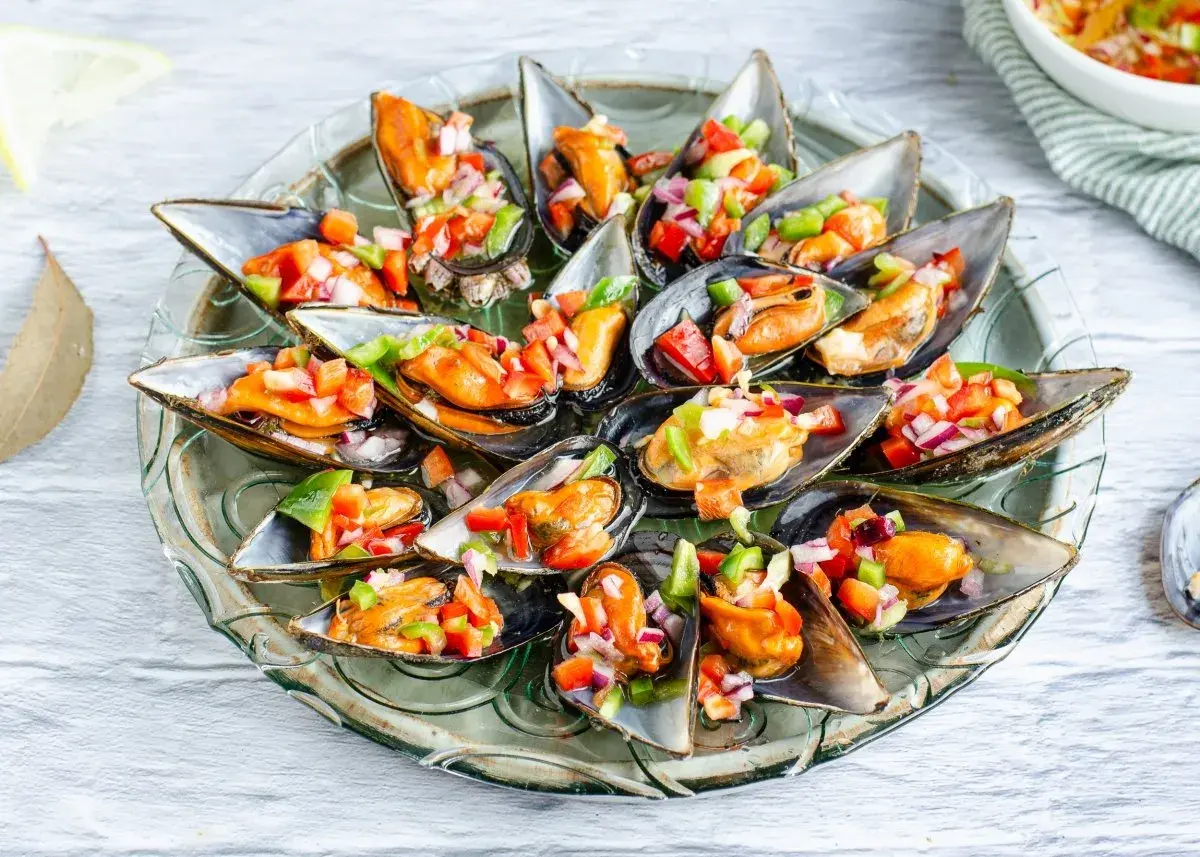Mejillones a la vinagreta, frescos y coloridos, servidos en una bandeja de cristal.