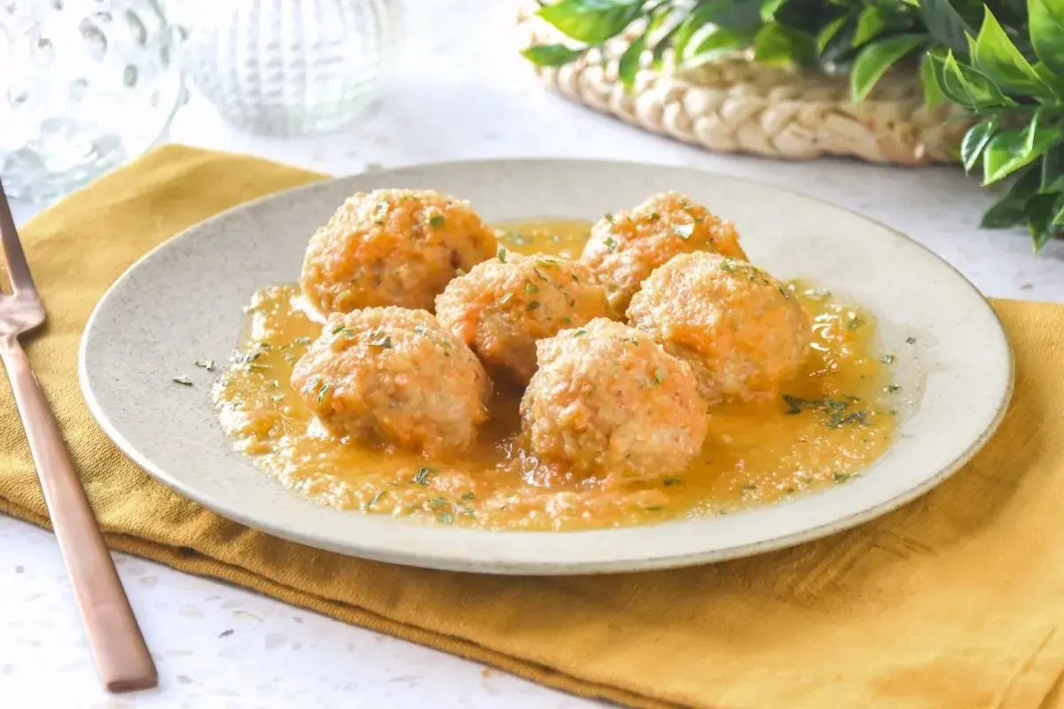 Sabrosas albóndigas de pollo en una salsa dorada, espolvoreadas con perejil fresco. Un plato casero listo para disfrutar.