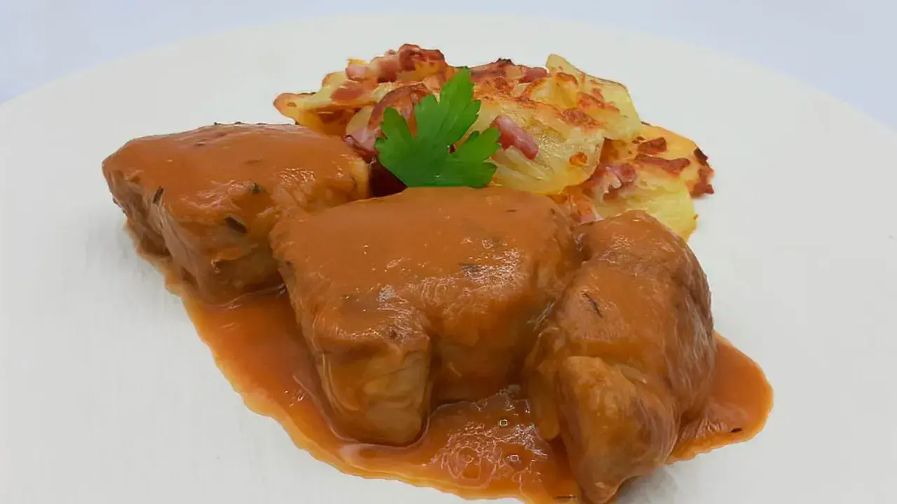 Solomillo de cerdo a la cerveza bañado en salsa, acompañado de patatas gratinadas con bacon y perejil.
