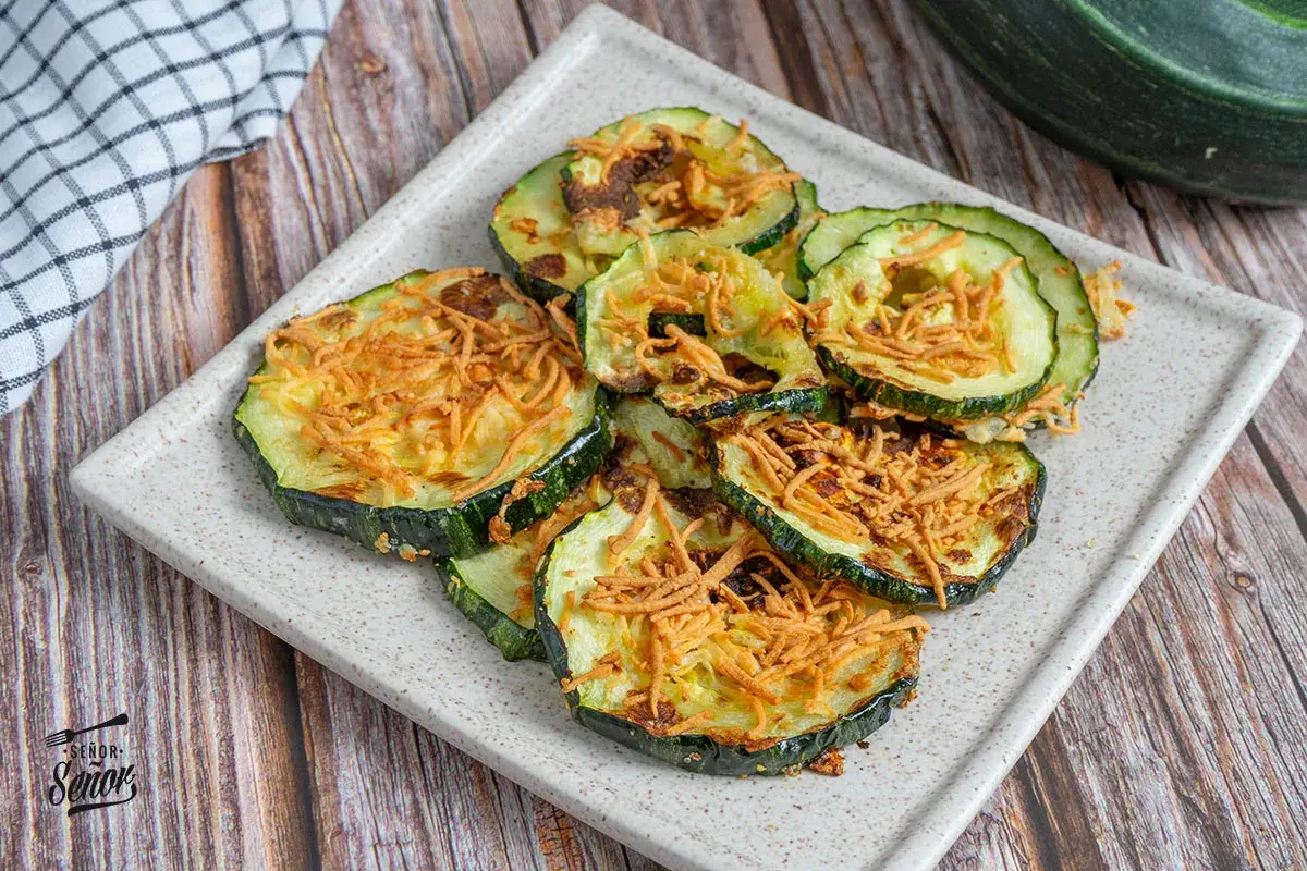 Rodajas de calabacín airfryer crujientes y doradas, espolvoreadas con queso rallado. ¡Un aperitivo saludable y delicioso!