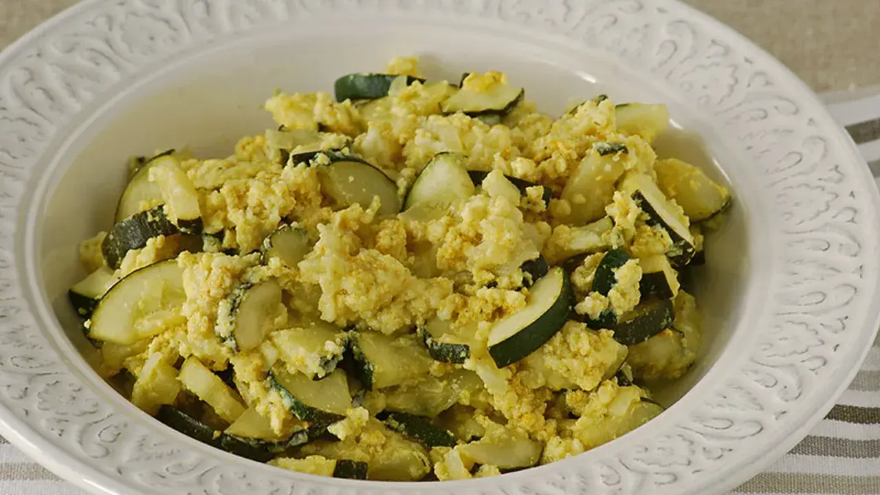Zarangollo murciano, un plato casero de calabacín y huevo revuelto, servido en un cuenco blanco con relieve.