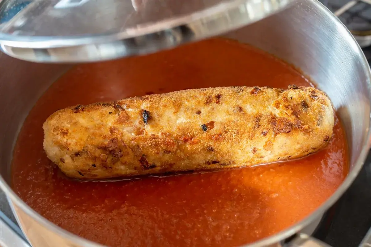 Rollo de bonito casa consuelo, dorado y crujiente, nadando en una salsa de tomate casera en una sartén.