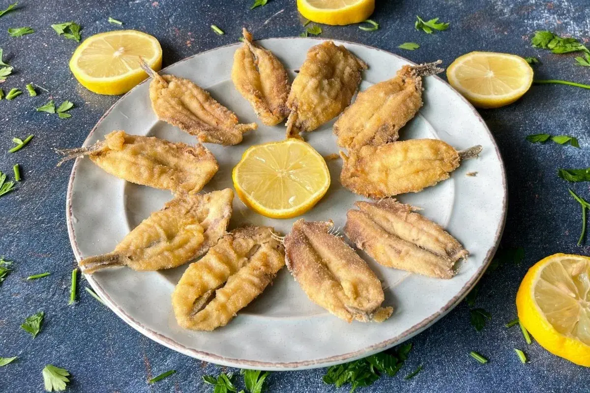 Plato de boquerones fritos crujientes, adornado con rodajas de limón y perejil fresco. Un aperitivo perfecto.